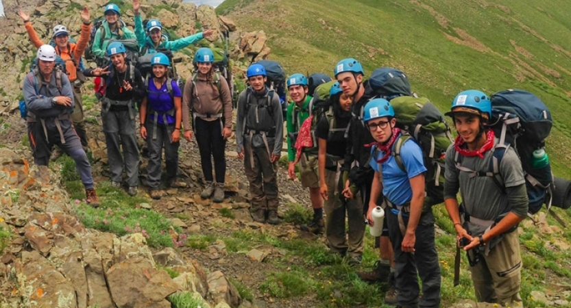 a group of backpackers stand among a grassy and rocky landscap